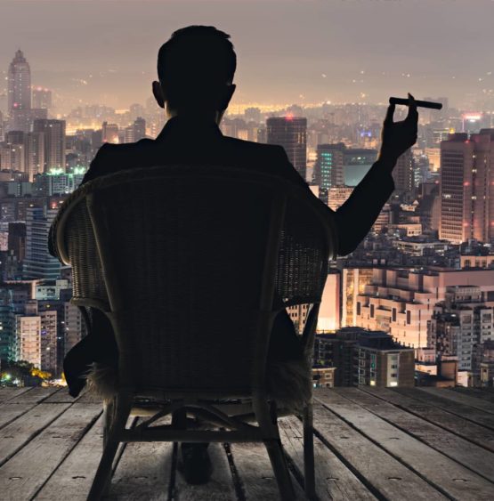 man-sitting-with-cigar-looking-at-the-city-skyline