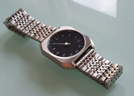metal one hand watch on a glass table